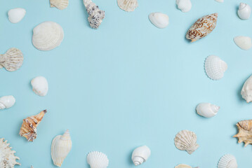White shells on sky blue surface with copy space in the middle. Summer, top view, flat lay composition