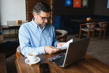 Business, technology and people concept , senior businessman with laptop computer drinking coffee at modern cafe.