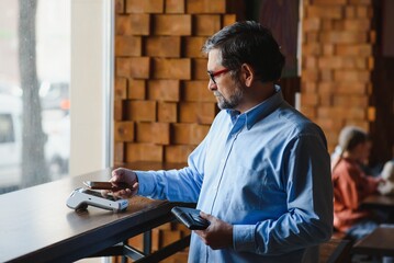 Mature businessman paying with contactless credit card with NFC technology.