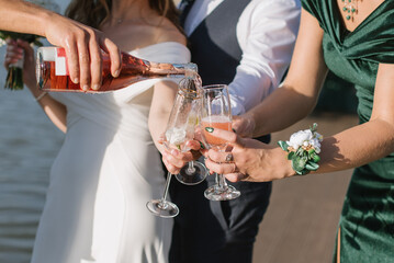 Bride and groom, bridesmaid and best men holding glasses of wine on wedding day. Close up
