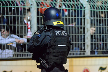Symbolbild behelmter Bereitschaftspolizist zur Absicherung vor Fanblock im Fußballstadion