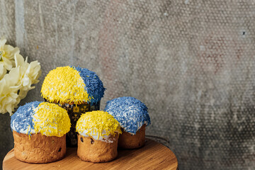 Delicious Easter cakes in the colors of the flag of Ukraine on a wooden table with flowers in the background. place for text. selective focus