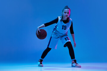 Plakat Portrait of teen girl, basketball player in motion, dribbling ball isolated over white studio background. Active game
