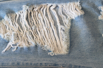 Jeans leg. Texture of torn blue denim fabric