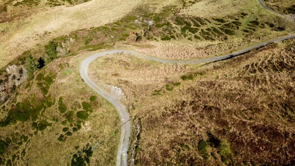 A drone shot of a pathway in Alps. The road is curvy, but steadily leading to the top. Golden...