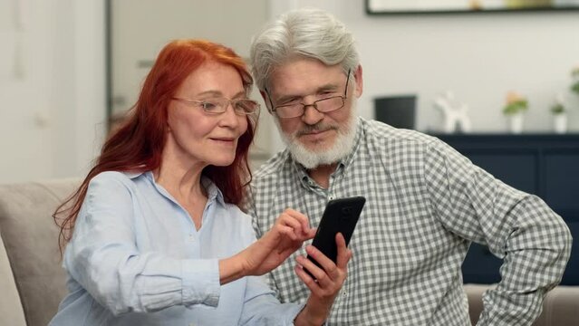 A senior couple in their 60s make an online purchase using a smartphone.