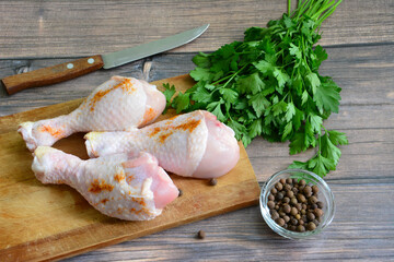raw chicken legs on cutting board with spices, close-up