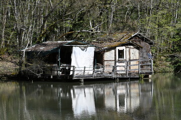 Abandoned fishing cabin, small damaged house over a lake.