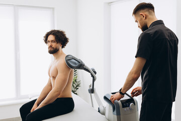 A sport man in a massage clinic where a massagist warms his muscles. New massage technologies 