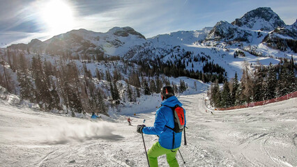 Morning in Alps, Nassfeld, Austria. Young skier stands on the graveled slope with his skies....