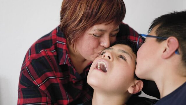 Happy mother having tender moment together his son with disability at home - Family love concept