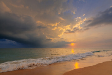 Naklejka na ściany i meble Gorgeous sunset sky with clouds over Indian ocean sandy beach with a foamy wave. Beautiful seascape.