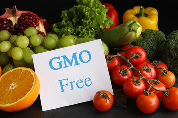 Tasty fresh GMO free products and paper card on black table