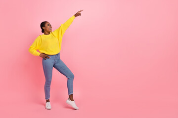 Full length photo of young girl have fun indicate finger empty space free-time isolated over pink color background