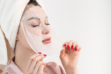 Face care and beauty treatments. Woman with a sheet moisturizing mask on her face isolated on white background