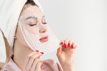 Face care and beauty treatments. Woman with a sheet moisturizing mask on her face isolated on white background