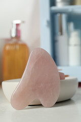 Rose quartz gua sha tool on white table, closeup
