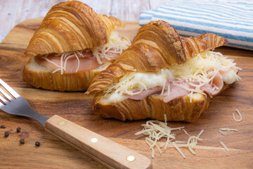 close up of croissant with cured ham on a wooden board