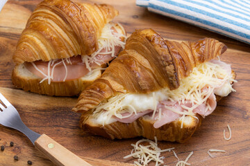 close up of croissant with cured ham on a wooden board