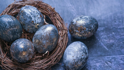 Easter card with a copy of the place for the text. Very Peri 2022 .Purple, blue eggs in a basket on a dark newspaper background. Natural dye karkade tea.