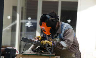 welder, blacksmith working with spot welder. with helmet and work clothes.