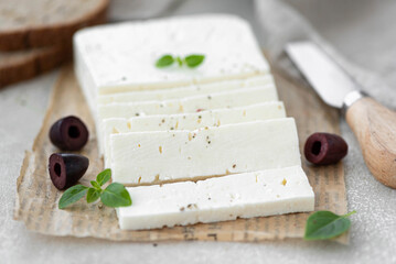 homemade feta cheese with olives and herbs on a wooden table