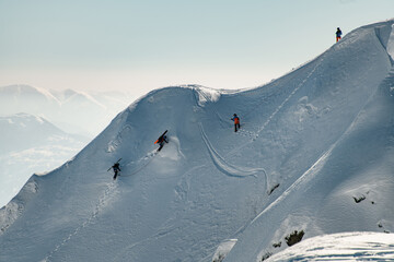 gorgeous view of mountain slope covered with snow along which groups of skiers climb