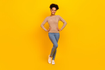 Fototapeta na wymiar Full size photo of nice young brunette lady stand wear pullover jeans sneakers isolated on yellow color background