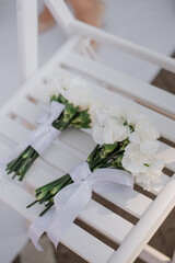 Beautiful white bridesmaids bouquets lay on the ceremony white wooden chair
