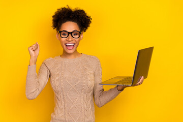 Photo of hooray young brunette lady hold laptop yell wear eyewear beige pullover isolated on yellow color background