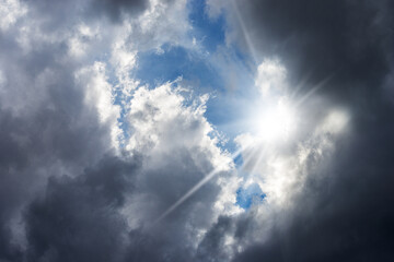 Close-up of a dark dramatic cloudy sky with sunbeams, backlit, full frame, photography. 