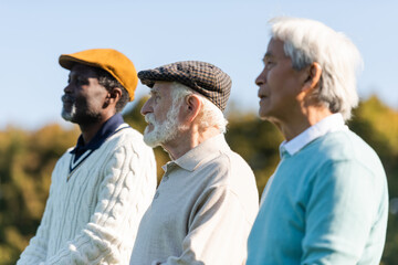 senior man in flat cap near interracial friends.