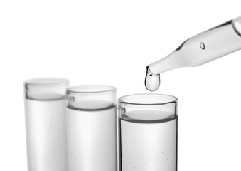 Dripping transparent liquid into test tube on white background, closeup