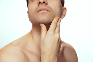 Cropped portrait of man with perfectly shaved skin, touching face isolated over white studio background.