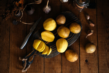 Raw fresh new potatoes on a wooden background. Sliced potatoes. Rustic style.