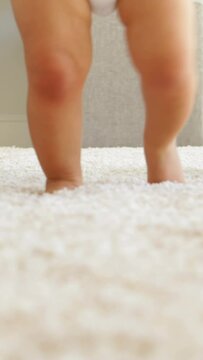 Father helping baby to walk across rug