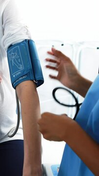 Mid section of doctor checking blood pressure of pregnant woman