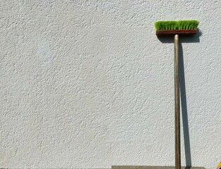 a scrubber leaning against a white wall