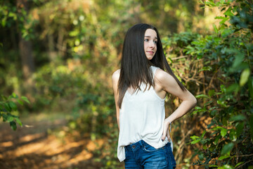 Fototapeta premium A beautiful serious teen brunette girl looking away from the camera towards the future in a wooded area in the spring
