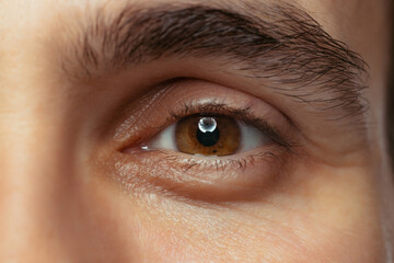 Cropped close-up portrait of beautiful male brown eyes looking at camera. Calm, attentive look.