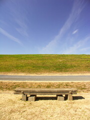 Obraz premium 早春の河川敷の石のベンチと砂利道と江戸川土手風景