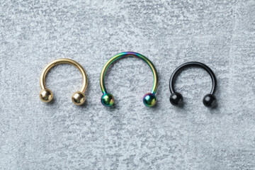 Stylish horseshoe rings on light grey table, flat lay. Piercing jewelry