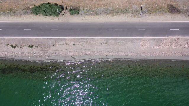  Aerial top view asphalt road highway near lake. Drone view a road  parallel with a Sevan lake, Armenia, Caucasus.
The rays of the sun reflect on the sea․ Touristic place, Discovery Armenia. 