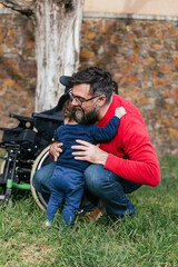 A loving father cuddling his little son on the grass in a park
