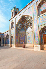 Obraz premium Woman in traditional abaya standing in the Nasir al-Mulk Mosque (Pink Mosque) reflected in pool in the middle of courtyard in Shiraz, Iran - Also famous as Pink Mosque
