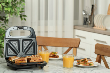 Modern grill maker with sandwiches and breakfast served on white marble table in kitchen - obrazy, fototapety, plakaty