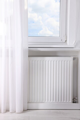 Modern radiator on wall under window indoors. Central heating system