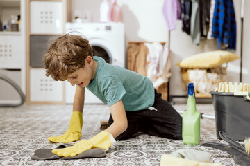 Young child using cloth and liquid at home. Smiling boy mopping apartment floor, doing housework,...