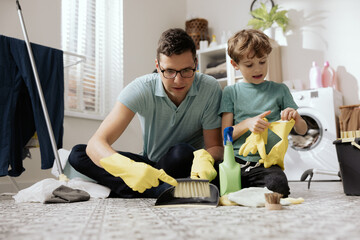 Handsome young man wiping dance floor. Concept of husband cleaning and running house. Interior of...