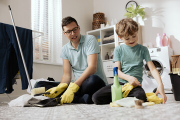 Handsome young man wiping dance floor. Concept of husband cleaning and running house. Interior of...
